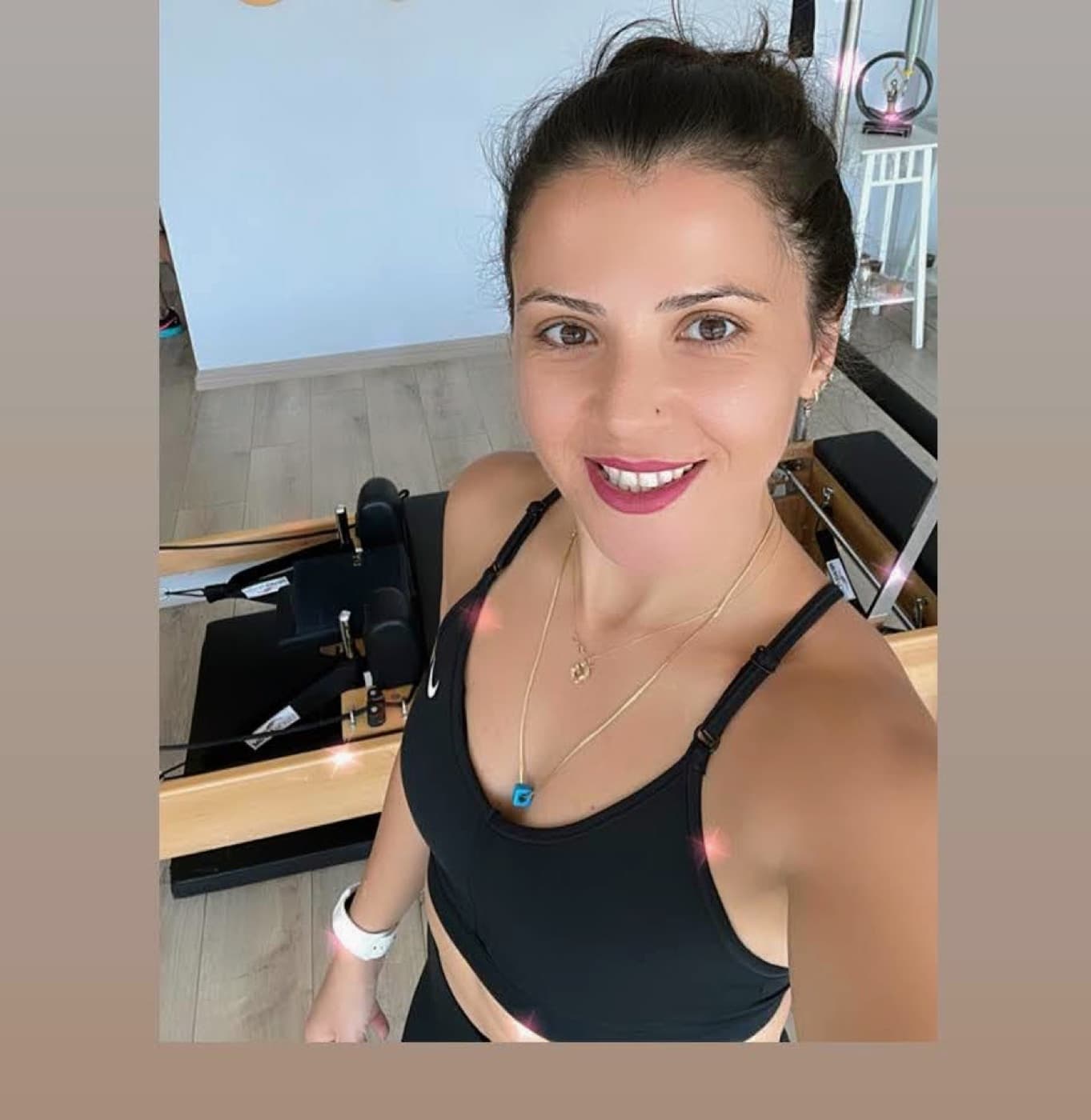 Gülçin smiling beside a reformer in her studio